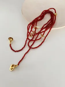 Detail view of a long red agate beaded necklace with elegant gold trumpet-shaped accents
