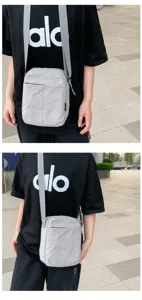 Detailansicht einer grauen minimalistischen Nylon-Umhängetasche auf schwarzem T-Shirt.