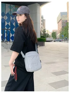 Model trägt eine lichtgraue minimalistische Umhängetasche in einer urbanen Straße
