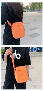Nahaufnahme einer orangefarbenen minimalistischen Handy-Umhängetasche getragen in der Stadt