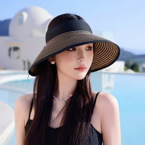 Modisches gestreiftes Stroh-Sonnenvisier für Damen in einer sommerlichen Außenanlage am Pool