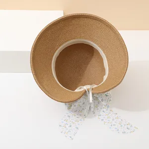 Macro interior view of a pastoral straw sun hat featuring a blue floral ribbon bow.