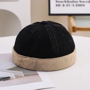 Detailed view of a vintage black and khaki brimless landlord miki hat on a white table