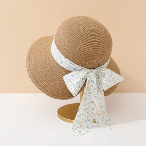 Close-up of a straw sun hat with a delicate floral bow ribbon on a display stand.
