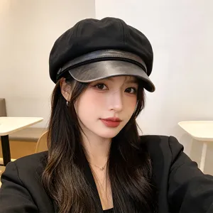 Detail view of a vintage black newsboy hat with a leather brim worn by a model