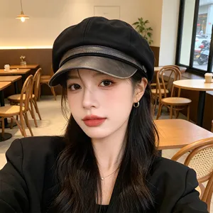 Close-up of a stylish black PU leather newsboy cap worn by a model in a cafe.