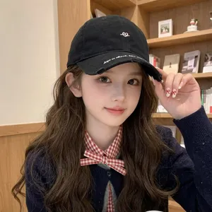 Close-up of a black cotton baseball cap with white heart embroidery worn by a model