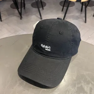 Primo piano di un cappellino da baseball nero lavato con ricamo apen MIND bianco