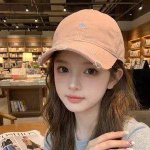 Close-up of a stylish pink retro baseball cap with cute heart embroidery worn by a young woman
