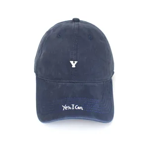 Navy blue cotton baseball cap detail with white Y embroidery and slogan brim stitching.