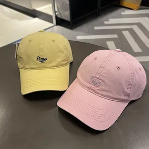 Dettaglio di cappellini da baseball in cotone lavato giallo e rosa con ricamo Pious