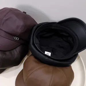 Close-up of various PU leather newsboy caps in burgundy, black, and brown colors.