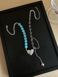 Detailansicht der asymmetrischen Halskette mit blauen Katzenaugenperlen und Herz.