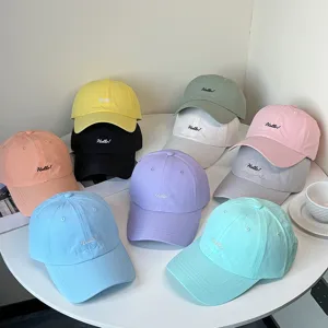 Detailansicht verschiedener bunter Baseballkappen mit eingesticktem Hello!-Logo.