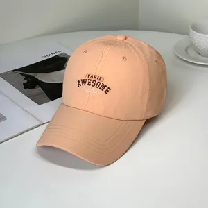 Close-up of peach embroidered baseball cap with 'Paris Awesome' lettering