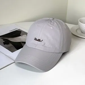 Detailansicht einer grauen Baseballkappe mit schwarzer Hello!-Stickerei vorne