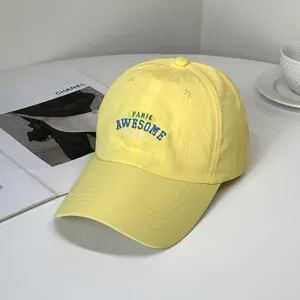 Macro view of yellow quick-dry baseball cap with blue 'AWESOME' letter embroidery