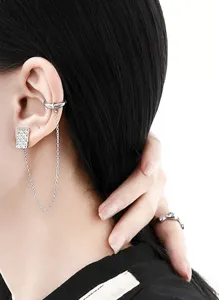 Détail montrant le clou d'oreille et le ear cuff reliés par une chaîne au motif argenté.