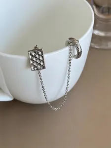 Gros plan d'un clou d'oreille floral argenté relié à une boucle d'oreille par une chaîne