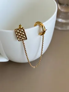 Vue détaillée d'une boucle d'oreille chaîne dorée avec trèfle et manchette d'oreille