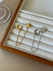 Détail de clou d'oreille et manchette intégrés avec chaîne et motif rectangulaire