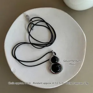 Close-up of black agate hulu pendant with an adjustable black wax cord necklace