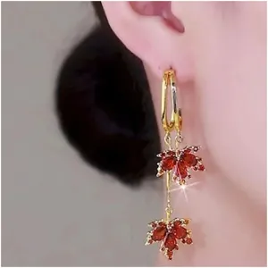 Detailed view of elegant red zircon maple leaf drop earrings worn on a model's ear