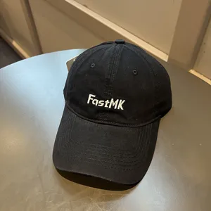 Detalle del bordado blanco 'FastMK' en una gorra de béisbol negra de estilo clásico