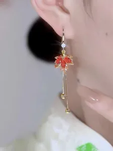 Close-up of red maple leaf dangle earring featuring sparkling crystals on gold chain
