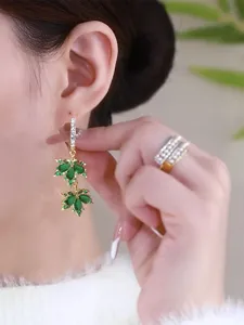 Close-up of luxury green maple leaf drop earrings with crystals on an Asian model