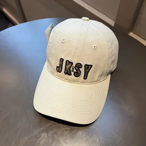 Vista detallada de una gorra de béisbol beige con bordado de letras de camuflaje JKSY