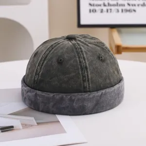 Close-up detail of a vintage washed charcoal grey brimless docker cap with distressed texture