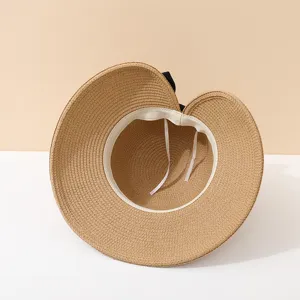 Detail view of a straw sun hat featuring inner sweatband and adjustable tie strings.