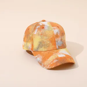 Gros plan de la casquette tie-dye orange montrant la texture du tissu et la visière.