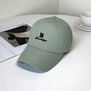 Detailed view of light green quick-dry baseball cap with black Brooklyn embroidery.