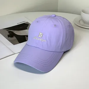 Close-up detail of a purple quick-dry baseball cap with white Brooklyn embroidery.