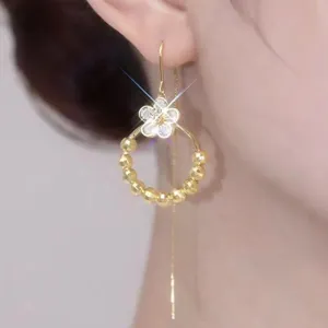 Detail view of sparkling flower tassel earrings with golden beads and long chain