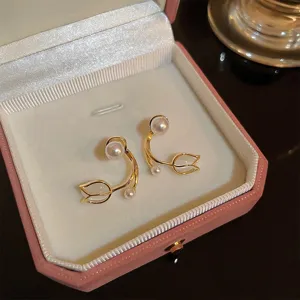Close-up of elegant tulip-shaped gold earrings with pearls in a pink jewelry box.