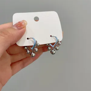 Close-up of minimalist silver hoop earrings featuring hanging metal beads