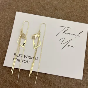 Detailed view of gold geometric tassel threader earrings with YES letter engraving.