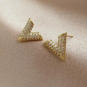 Close-up of elegant gold-toned V-shaped stud earrings paved with sparkling crystals