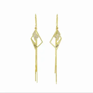 Detailed view of geometric gold earrings with tassel and 'YES' engraving.
