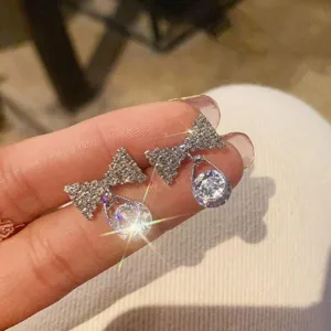 Close-up detail of sparkling silver bowknot earrings with teardrop crystal pendant