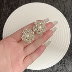 Élégantes boucles d'oreilles fleurs en perles blanches tenues à la main avec perle.