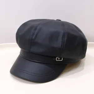 Close-up of vintage black PU leather baker boy hat with decorative metal buckle