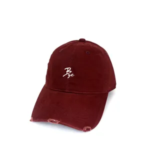 Close-up of the distressed brim and white embroidered Bye logo on this casual maroon cap.