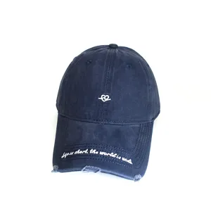 Detailed macro view of white embroidery and distressed brim on navy blue baseball cap.