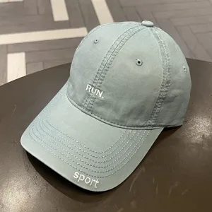 Vista dettagliata del cappello da baseball lavato con ricamo bianco 'RUN.' e 'sport'