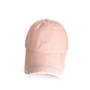 Detailed view of pink baseball cap featuring heart embroidery and distressed brim