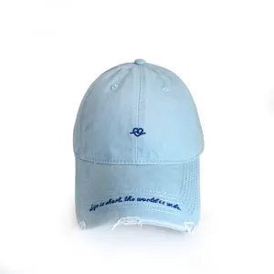 Detail of light blue baseball cap with embroidered heart and cursive text on brim